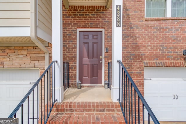 entrance to property with a garage and brick siding