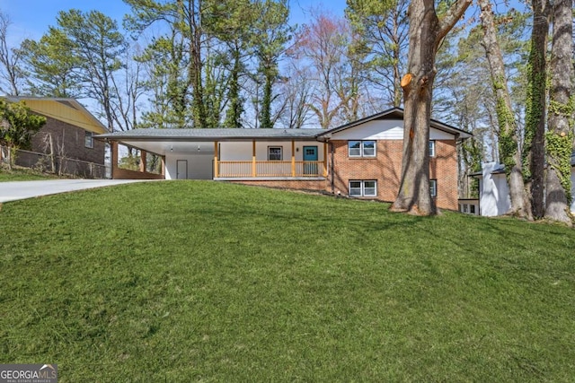 view of front of home with concrete driveway, an attached carport, a front yard, and brick siding