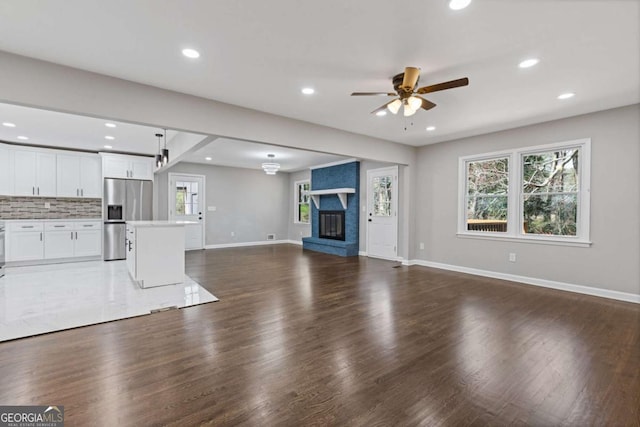 unfurnished living room featuring recessed lighting, a large fireplace, baseboards, and wood finished floors