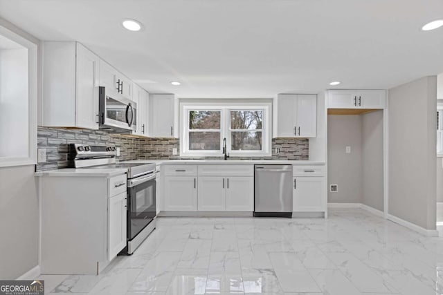 5277 Cardinal Ln NW, Lilburn, GA 30047 - kitchen featuring appliances with stainless steel finishes, light countertops, white cabinets, backsplash, and light marble finish flooring