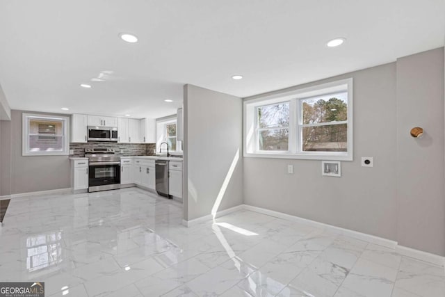 kitchen featuring white cabinets, baseboards, marble finish floor, appliances with stainless steel finishes, and tasteful backsplash