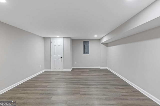 finished below grade area featuring recessed lighting, wood finished floors, electric panel, and baseboards