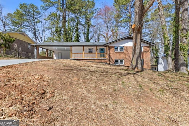 view of front of house with driveway, an attached carport, and brick siding