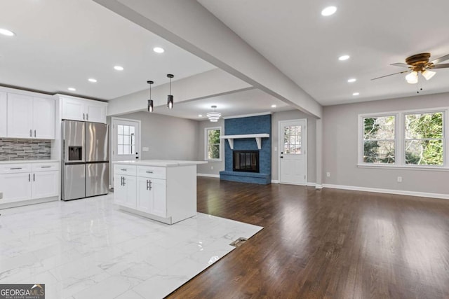 kitchen featuring open floor plan, baseboards, stainless steel fridge, and decorative backsplash