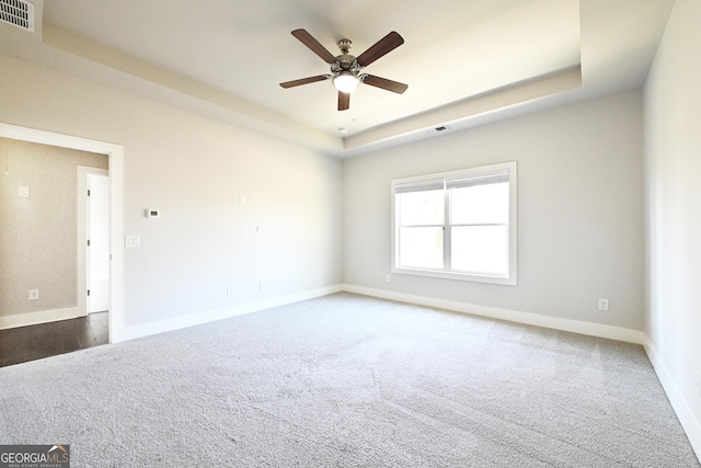 unfurnished room with a raised ceiling, baseboards, and visible vents