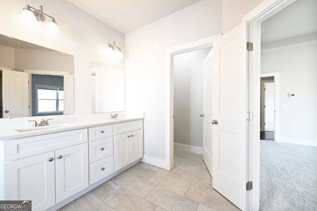 full bath with double vanity, baseboards, and a sink