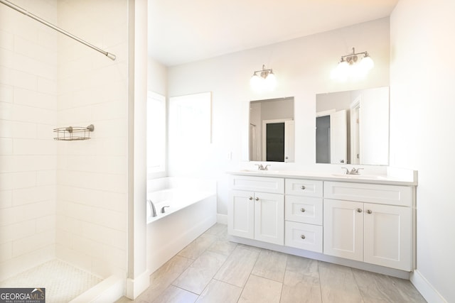 full bathroom featuring a bath, double vanity, a tile shower, and baseboards