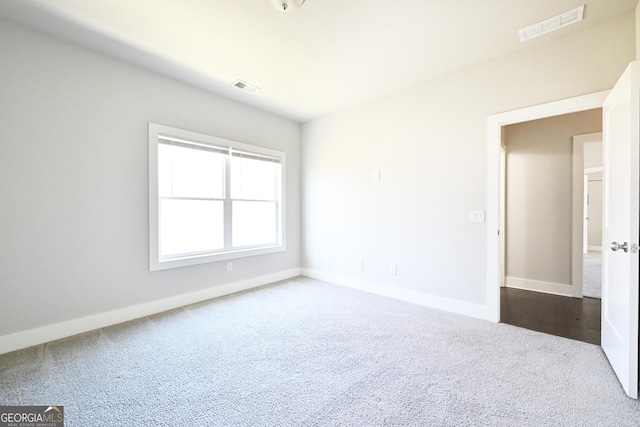 unfurnished room with dark carpet and baseboards