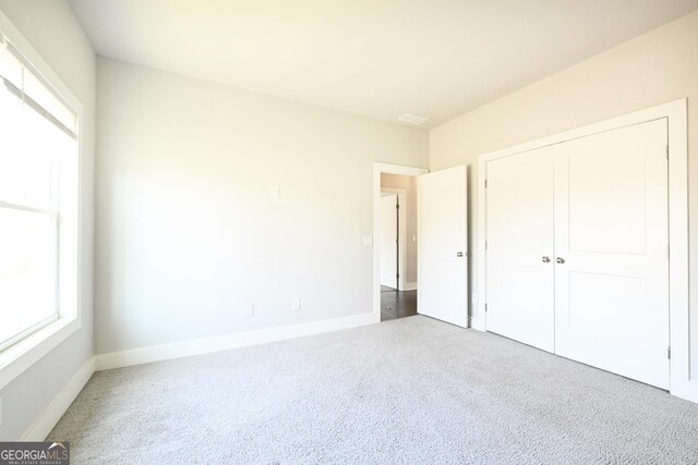 unfurnished bedroom with carpet, baseboards, and a closet