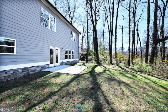 view of green lawn featuring french doors and a patio