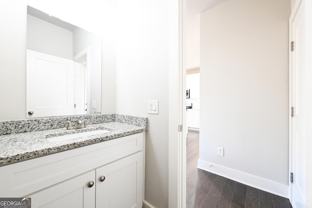 bathroom with vanity, wood finished floors, and baseboards