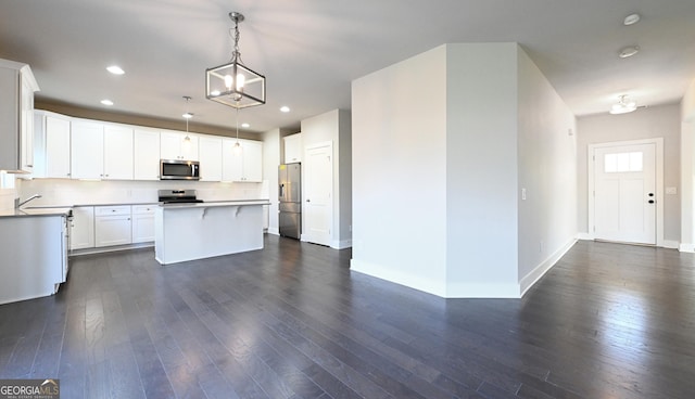 kitchen with dark wood-style floors, backsplash, appliances with stainless steel finishes, and a center island