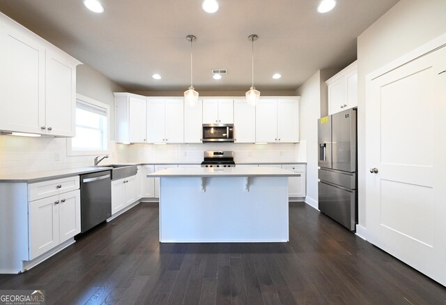 kitchen with dark wood-style floors, a kitchen island, appliances with stainless steel finishes, and a sink