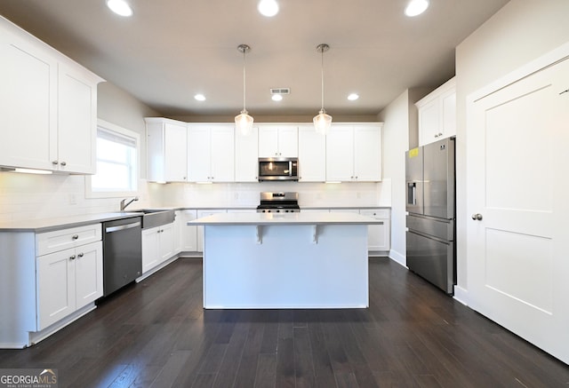 kitchen with appliances with stainless steel finishes, a sink, a center island, white cabinetry, and light countertops