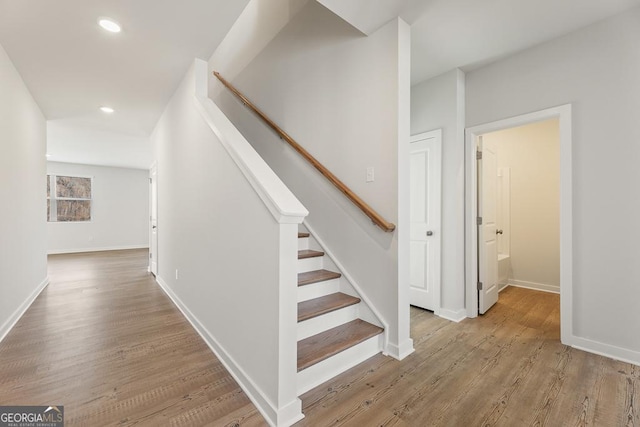 staircase with baseboards, wood finished floors, and recessed lighting