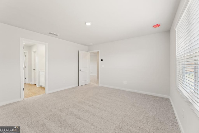 unfurnished bedroom featuring light colored carpet, visible vents, baseboards, and recessed lighting