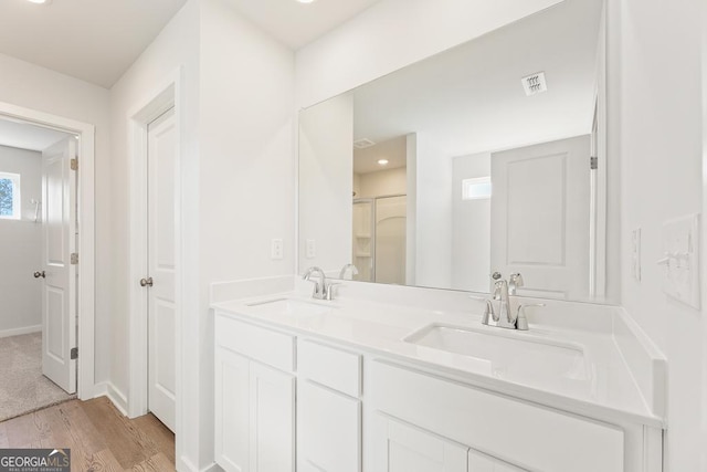 bathroom featuring double vanity, visible vents, a sink, and wood finished floors