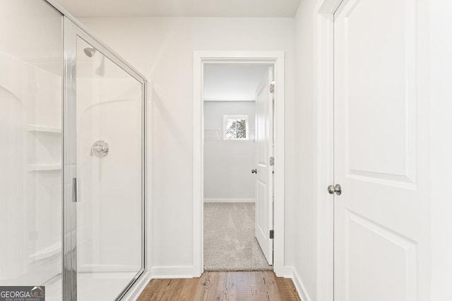 bathroom with a stall shower, baseboards, and wood finished floors