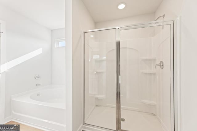 bathroom featuring a garden tub and a shower stall