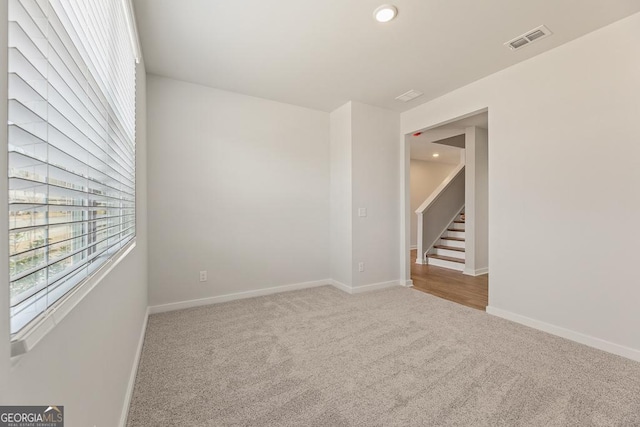 carpeted empty room with recessed lighting, visible vents, stairway, and baseboards