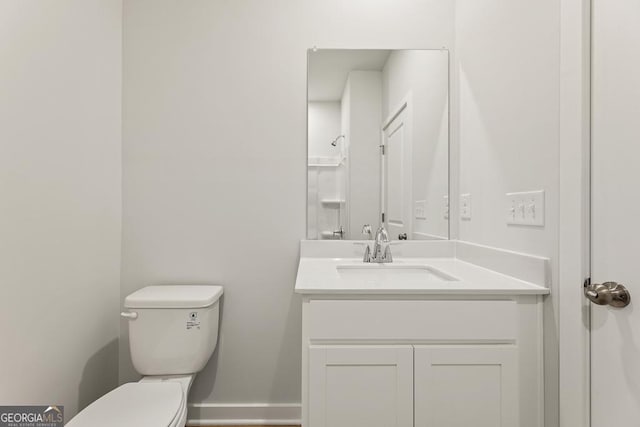 bathroom featuring a shower, baseboards, vanity, and toilet