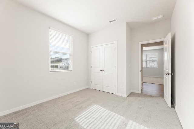 unfurnished bedroom featuring a closet, carpet flooring, visible vents, and baseboards