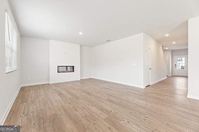 unfurnished living room featuring light wood-style floors, recessed lighting, a large fireplace, and baseboards