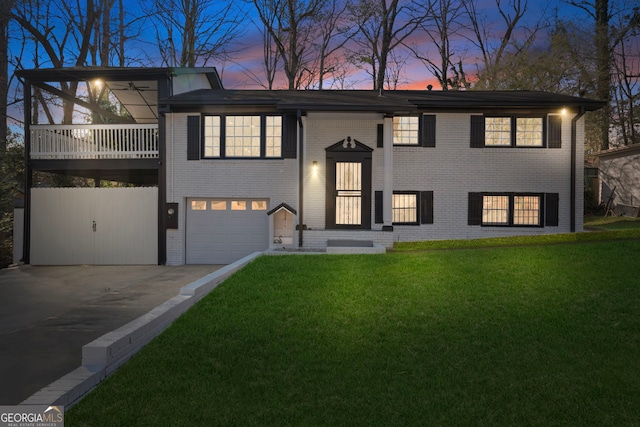 split foyer home featuring a garage, concrete driveway, brick siding, and a front lawn