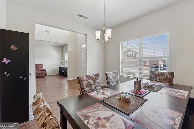 dining room featuring visible vents, wood finished floors, and a chandelier