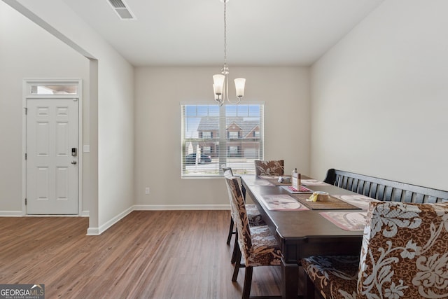 dining area with visible vents, baseboards, wood finished floors, and a chandelier