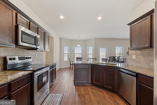 kitchen featuring dark wood-type flooring, a sink, appliances with stainless steel finishes, a peninsula, and dark brown cabinets