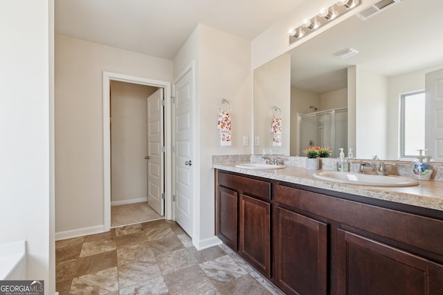 bathroom featuring a shower stall, double vanity, visible vents, and a sink