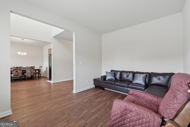 living area featuring dark wood finished floors, a chandelier, and baseboards