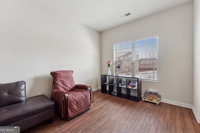 living area featuring visible vents, baseboards, and wood finished floors