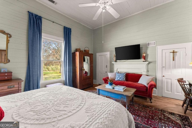 bedroom with crown molding, visible vents, ceiling fan, and wood finished floors