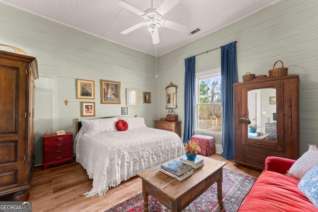 bedroom featuring light wood-style flooring, visible vents, and a ceiling fan