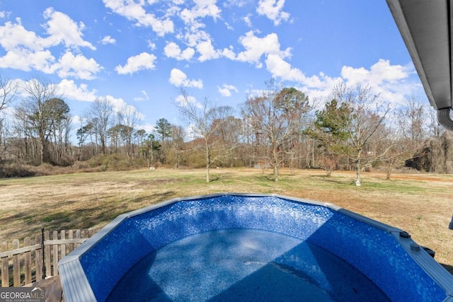 view of swimming pool featuring a yard, fence, and a jacuzzi