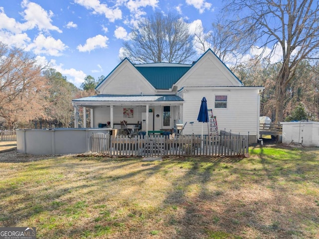 rear view of property featuring an outdoor pool, a yard, and metal roof