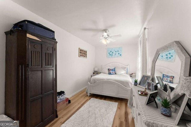 bedroom with light wood-style floors, ceiling fan, and baseboards