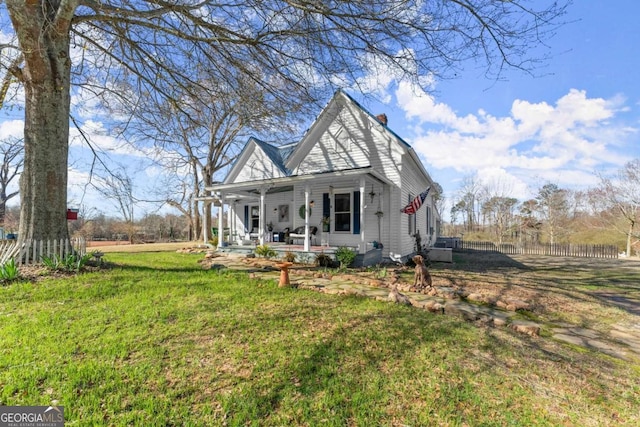 view of front of property featuring covered porch, a front yard, and fence