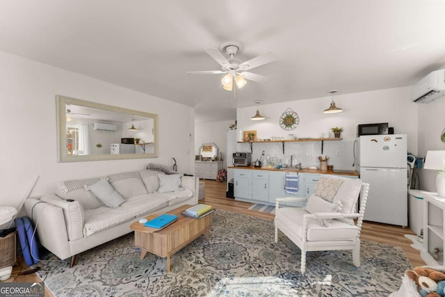 living area with light wood-style floors, a wall unit AC, ceiling fan, and a wall mounted AC