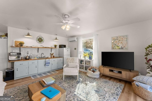 living area featuring light wood-style flooring, ceiling fan, and an AC wall unit