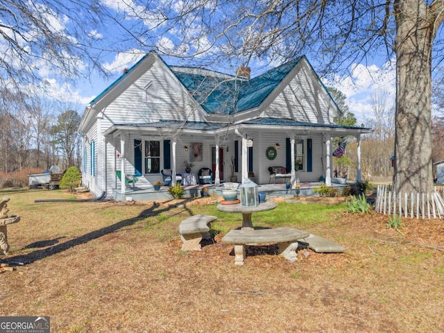 view of front of property with a porch, a chimney, and a front lawn