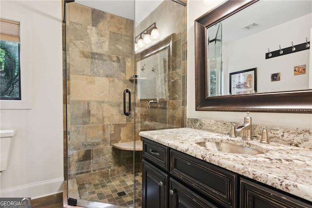 full bath featuring visible vents, toilet, a stall shower, vanity, and baseboards