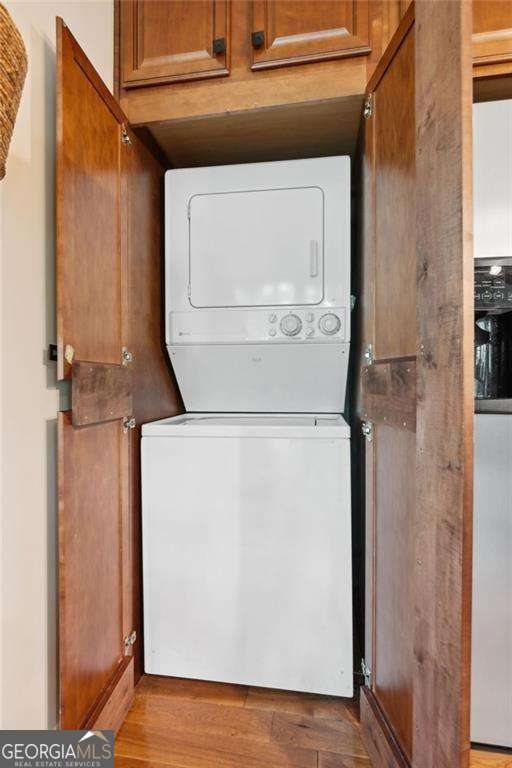 laundry area featuring laundry area, stacked washer / dryer, and wood finished floors