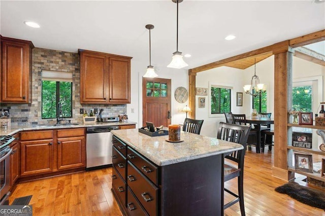 kitchen featuring vaulted ceiling with beams, a breakfast bar, appliances with stainless steel finishes, light wood-type flooring, and backsplash