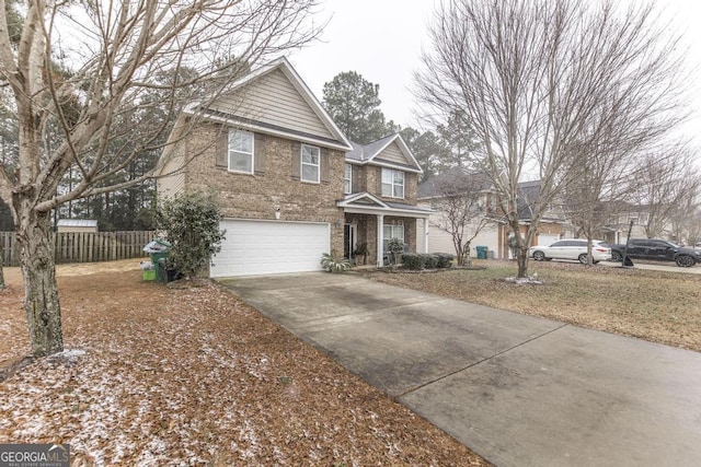 traditional-style house featuring a garage, driveway, brick siding, and fence