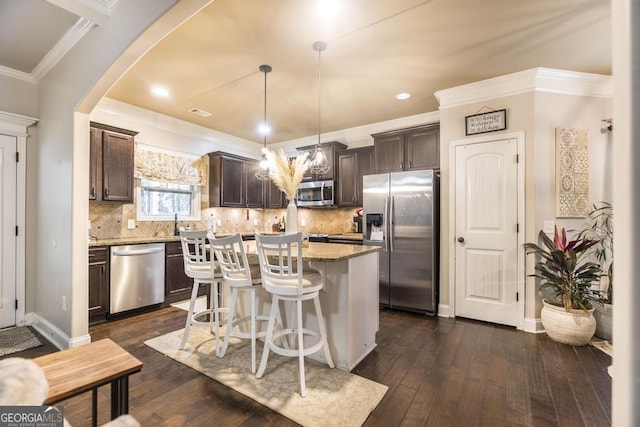 kitchen featuring a kitchen breakfast bar, dark brown cabinets, appliances with stainless steel finishes, a center island, and crown molding