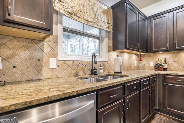 kitchen featuring dark brown cabinetry, tasteful backsplash, dishwasher, light stone countertops, and a sink