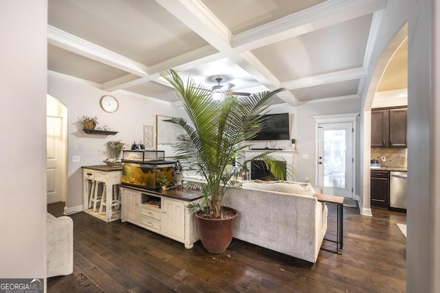 living room featuring arched walkways, dark wood-type flooring, ornamental molding, coffered ceiling, and beamed ceiling